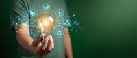 Male hand holding glowing light bulb with green energy icons, sustainability concept on dark green background for eco innovation.