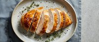 Sliced roasted chicken breast with herbs on ceramic plate, ready-to-eat protein meal for cooking and food styling.
