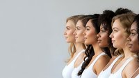Diverse group of young women in white tops standing in profile line showing multicultural beauty and unity for skincare cosmetics advertising campaigns.