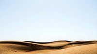 Desert sand dunes landscape with smooth golden curves against clear sky for travel and nature backgrounds.