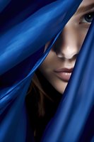 Young Asian woman's face partially hidden behind flowing blue silk fabric, creating mysterious and dramatic portrait with focus on eye and lips against dark background.