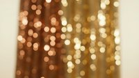 Blurred golden bokeh lights background with warm glowing circles, festive shimmering curtain effect for holiday, party, or celebration designs.