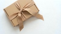 Kraft cardboard gift box tied with a satin ribbon bow on white background, perfect for holiday, birthday, and special occasion packaging.