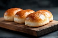 Fresh homemade dinner rolls with golden brown crust served on wooden cutting board against dark background, soft and fluffy bread buns for restaurant menu.