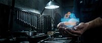 Industrial worker hands holding glowing digital technology hologram in dark manufacturing facility with machinery and dramatic lighting for innovation concepts.