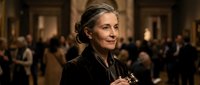 Elegant senior woman with gray hair in formal black attire at upscale evening event with blurred crowd background for luxury lifestyle concepts.