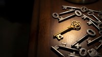 Collection of vintage antique keys on wooden surface with golden ornate key as centerpiece for security and mystery concepts.