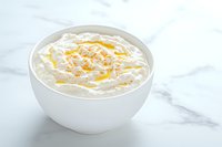 Creamy whipped ricotta cheese in white ceramic bowl drizzled with olive oil and seasoned with cracked pepper on marble surface, fresh appetizer serving.
