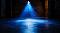 Dramatic blue spotlight beam illuminating dark empty stage with reflective floor surface creating atmospheric theatrical lighting effect and mysterious ambiance.