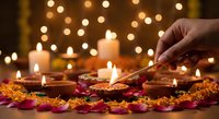 Hand lighting traditional oil lamps with colorful flower petals during festive celebration with warm bokeh lights creating magical atmosphere for ceremonies.