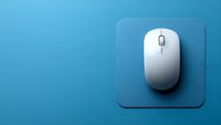 White wireless computer mouse on blue mousepad against gradient blue background, minimalist composition for technology and office concepts.