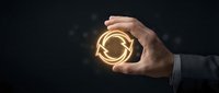 Businessman hand holding glowing circular arrow symbol representing refresh, renewal, and sustainable business cycle concept against dark background.