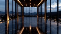 Modern luxury corridor with floor-to-ceiling windows overlooking mountain landscape at dusk, featuring dramatic lighting and reflective marble flooring creating symmetrical ambiance.