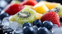 Fresh summer fruits with crushed ice cubes in macro view showing juicy strawberries, blueberries, kiwi and mango pieces for healthy eating concept.