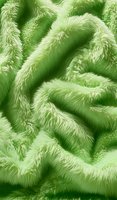 Soft green furry texture with wavy patterns creates abstract organic background. Seamless pattern suitable for fabric design and creative surface applications.