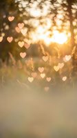 Romantic heart-shaped bokeh lights floating over warm golden sunset background with soft focus and dreamy atmosphere for Valentine's Day designs.