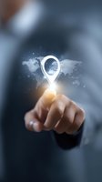 Businessman pointing at glowing location pin icon floating above world map background, concept of global positioning and international business navigation.