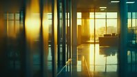 Modern office interior at sunset with glass walls and reflective floor creating dramatic lighting and shadows. Suitable for business and architecture concepts.