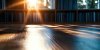 Dramatic sunlight streaming through window creates golden reflections on polished wooden floor surface with motion blur effect and bokeh background in empty room.