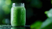 Fresh green smoothie with spinach and healthy ingredients in mason jar on dark background with water drops and bokeh effect.