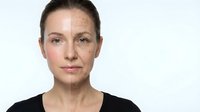Middle-aged Caucasian woman showing aging process with half face wrinkled and half smooth skin on white background for skincare and beauty concepts.