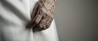 Elderly person with wrinkled hands wearing white clothing, showing aged skin texture and natural aging signs. Suitable for healthcare, wellness, and senior care concepts.