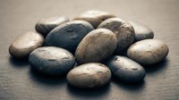 Smooth river stones in natural earth tones arranged on wooden surface for spa wellness meditation zen garden decoration and mindfulness practices.