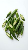 Fresh green okra pods whole and sliced showing seeds on white background. Healthy organic vegetable ingredient for cooking and nutrition concepts.