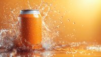 Orange soda can with water splash against warm golden background, droplets frozen in motion creating dynamic refreshment scene.