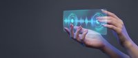 Hands holding transparent digital tablet with glowing sound wave and audio frequency visualization interface for music production and technology concepts.