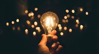 Hand holding glowing light bulb with warm bokeh lights in background symbolizing creativity innovation and bright ideas for business concepts.