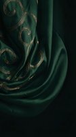 Luxurious emerald green silk fabric with elegant gold embroidered swirls and ornate patterns draped in flowing folds for premium textile and fashion design.