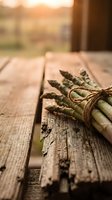 Fresh asparagus spears tied with twine on rustic wooden table with warm natural lighting for cooking and healthy eating concepts.