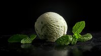 Creamy mint ice cream scoop with fresh green mint leaves on dark textured background, dramatic lighting creates appetizing dessert composition.