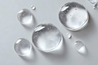 Clear water droplets with realistic reflections and transparency effects on clean white surface for modern design projects.
