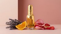 Luxury perfume bottle with gold cap surrounded by lavender, orange slice, and rose petals on pink background for beauty branding.