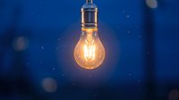 Glowing vintage incandescent bulb suspended against deep blue background with bokeh lights, symbolizing innovation, ideas, and energy solutions for creative projects.
