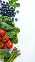 Fresh organic vegetables and blueberries arranged on white background with copy space for healthy eating and nutrition concepts.