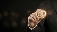 Young male professional in dark business suit holding glowing wedding rings symbol, representing marriage, commitment, engagement, and relationship concepts for corporate and lifestyle design use.