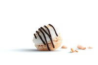 Delicate French macaron filled with cream and drizzled with dark chocolate sauce on white background with scattered crumbs, minimalist food photography.