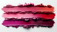 Smeared lipstick samples showing texture gradient from pink to red shades, crushed makeup swatches on white background displaying rich cosmetic pigments.