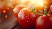 Fresh ripe cherry tomatoes with water drops on red surface against warm bokeh background, macro food photography for restaurant menu and cooking blogs.