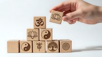 Hand arranging wooden blocks with spiritual symbols including lotus, om, yin yang, tree of life for meditation and mindfulness practices.