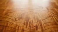 Close-up of natural wood grain texture with warm brown tones and organic patterns, showcasing detailed surface for interior design and crafting projects.