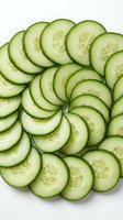 Fresh cucumber slices arranged in circular pattern on white background, healthy vegetable ingredient for salads, cooking and nutrition concepts.