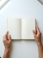 Hands holding open blank notebook with cream pages on white background, overhead view for journaling, writing, planning, and creative projects.
