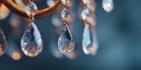 Elegant crystal chandelier with sparkling glass teardrops and warm golden metal frame creating luxurious ambient lighting for interior design projects.