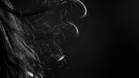 Dramatic black and white close-up of flowing hair strands with dynamic movement and texture against dark background for beauty and fashion concepts.