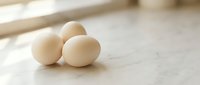 Fresh organic eggs on wooden kitchen counter with natural sunlight for healthy cooking and baking recipes.