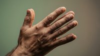 Mature male hand with detailed skin texture and visible veins against soft gradient background showing natural aging process and human anatomy.